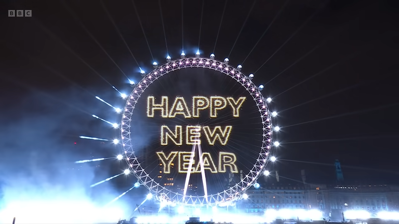 The London Eye on New Year's Day, surrounded by fireworks with the message 'Happy New Year' projected onto it.